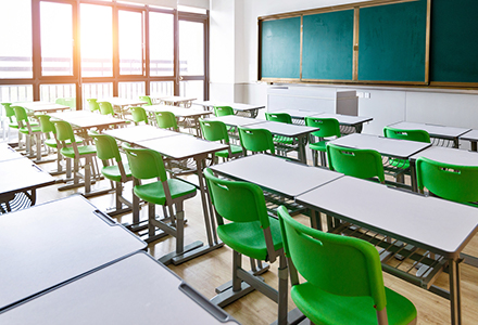 Photo of an empty classroom with desks, chairs, and a chalkboard