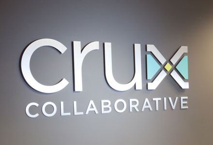 Wall sign for Crux Collaborative on a gray wall