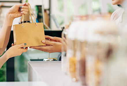 Customer receiving a shopping bag from a shopkeeper