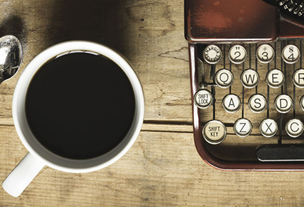 above view of a mug of coffee and typewriter