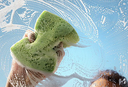 Person scrubbing a window with a sponge