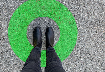 Photo looking down on feet standing in a painted circle on asphalt