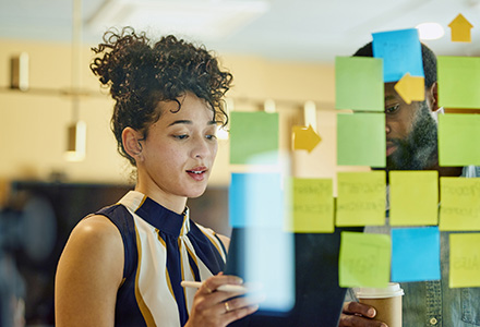 Woman and man looking at a glass pane full of Post-it notes