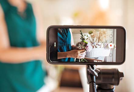Woman arranging flowers as seen through a phone taking video